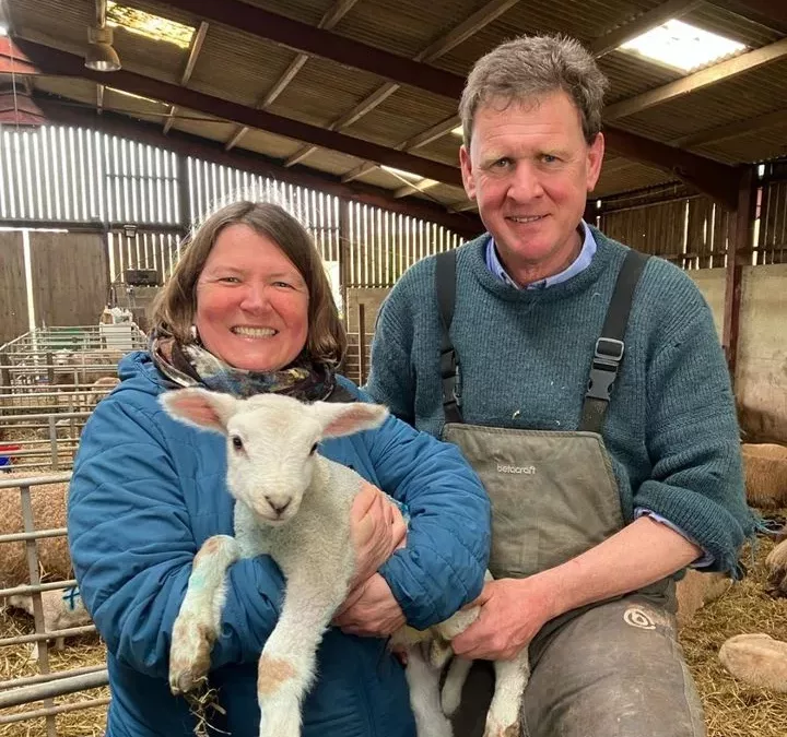 Ellie Chowns holds a lamb alongside farmer Bill Quan