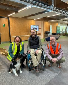 Ellie sitting with a service dog, and two more people from NMITE sitting with her