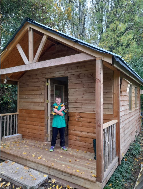 Boy standing with equipment at the door of the shed