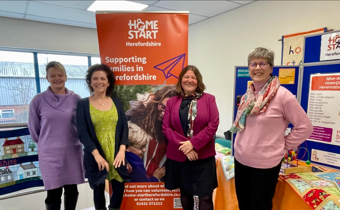 four people including Ellie Chowns are standing with the poster of Home Start