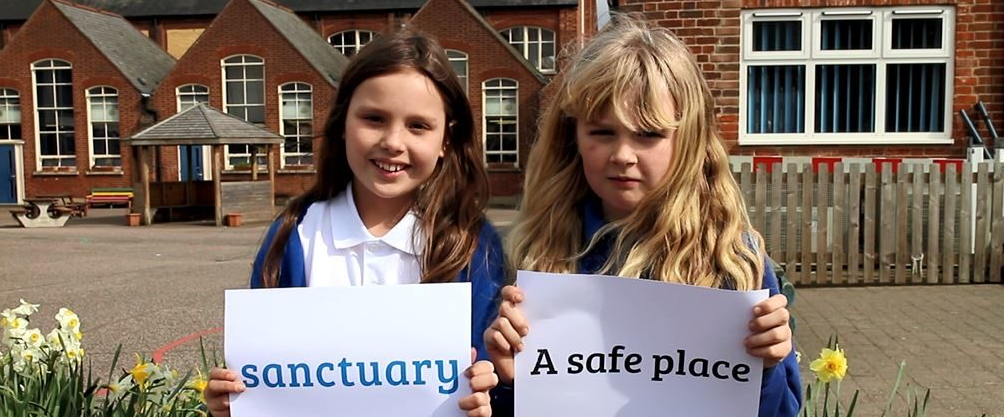 Two young girls stands together with posters sanctuary a safe place