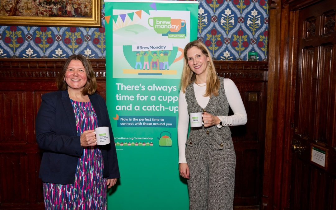 Ellie is standing with a young lady from Samaritans. Behind them is a poster of about Blue monday, and they are holding cups with the writing blue monday