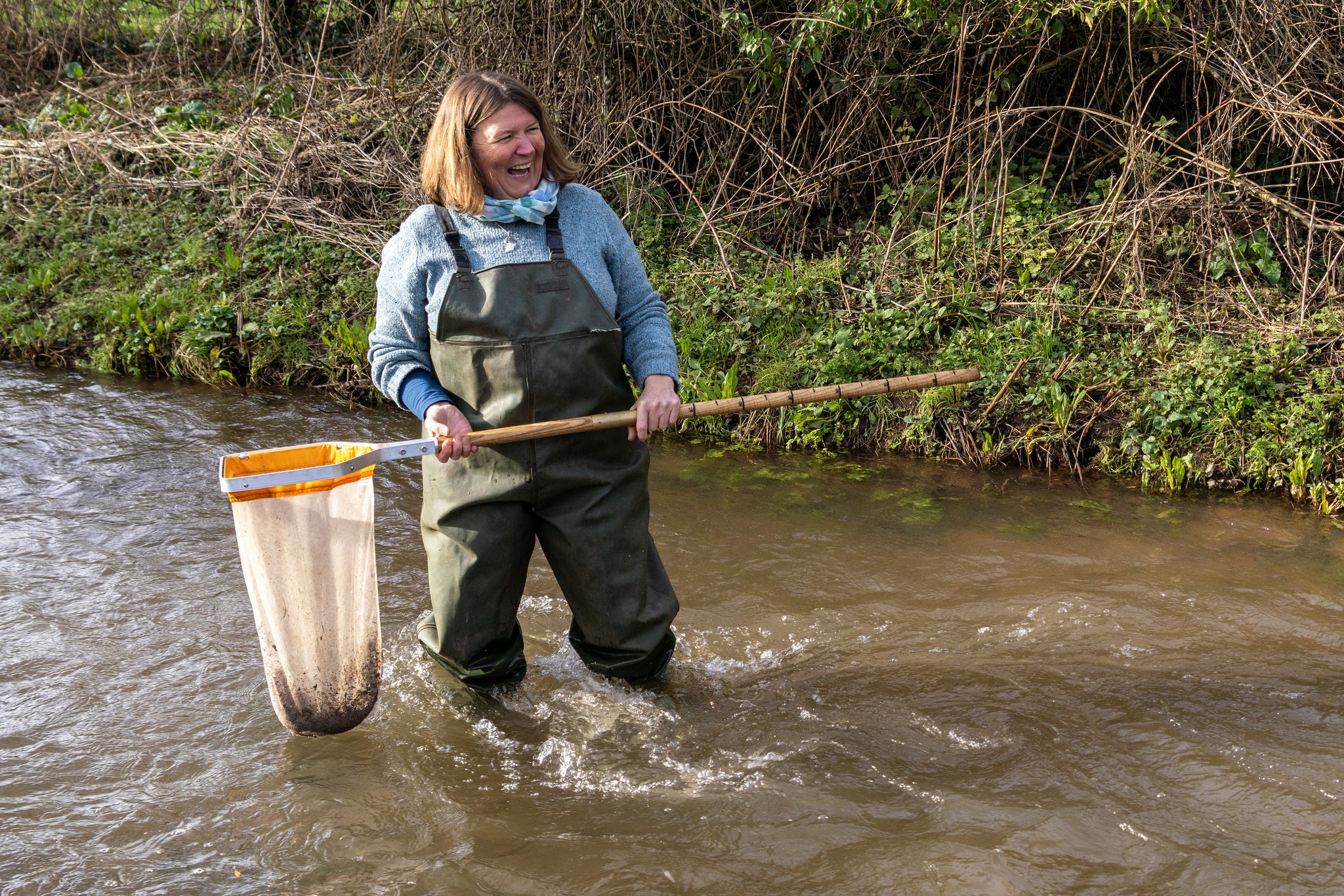 Ellie is standing in the river and holding the net with ground