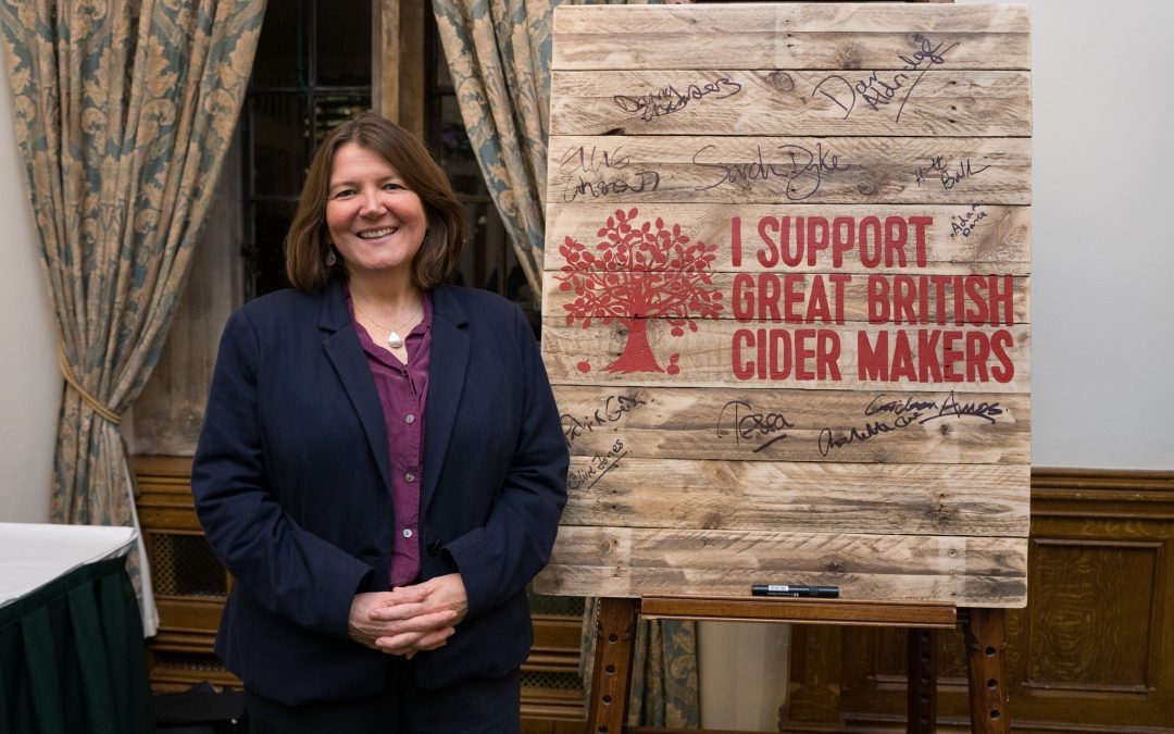 Ellie standing near the wooden sign which is stating I support great British cider maker