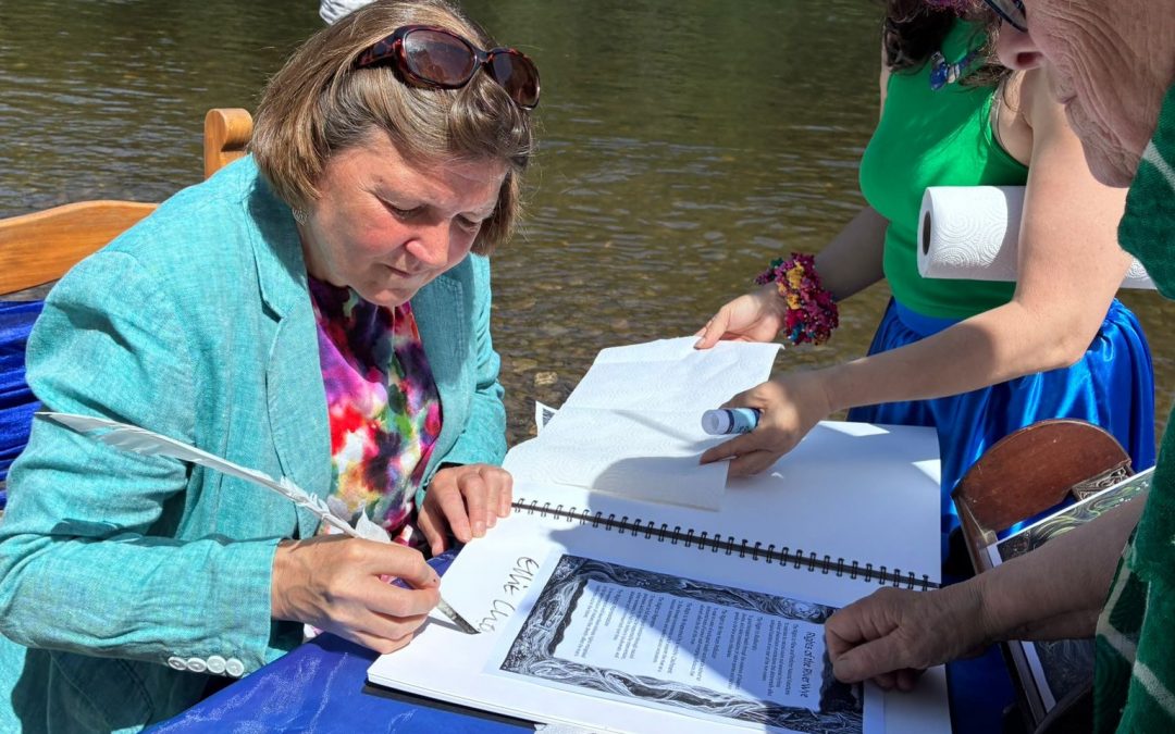 Ellie Chowns is signing the document near the river Wye